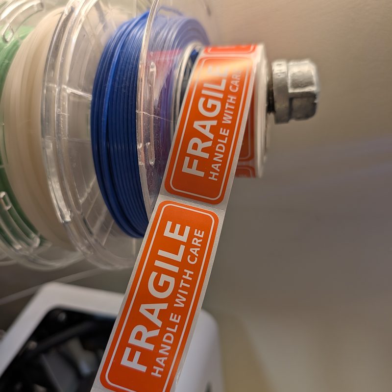 A roll of orange Fragile Handle With Care stickers